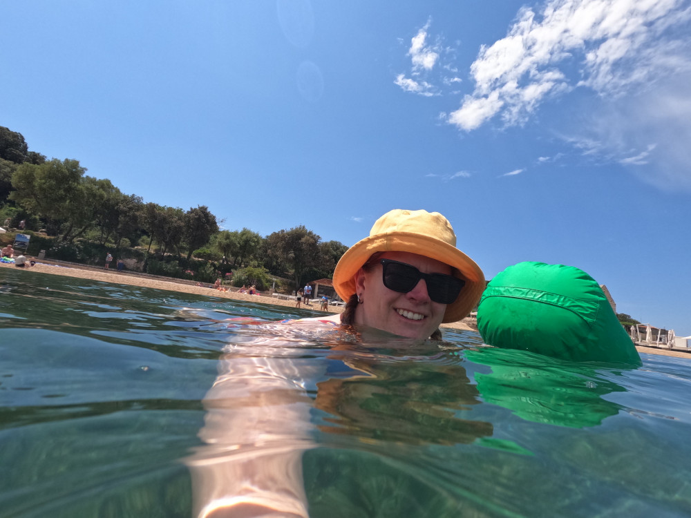 Swimming with the beach in the background, now deep enough that you can't really see anything apart from my head and arm. The drybag is floating behind me.