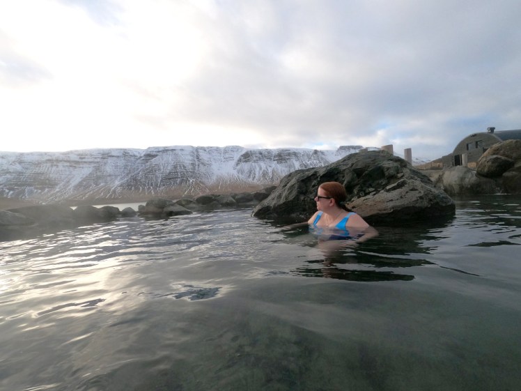 A timer selfie in a hot spring at Hvammsvik, with a ridge of snowy mountains behind me.