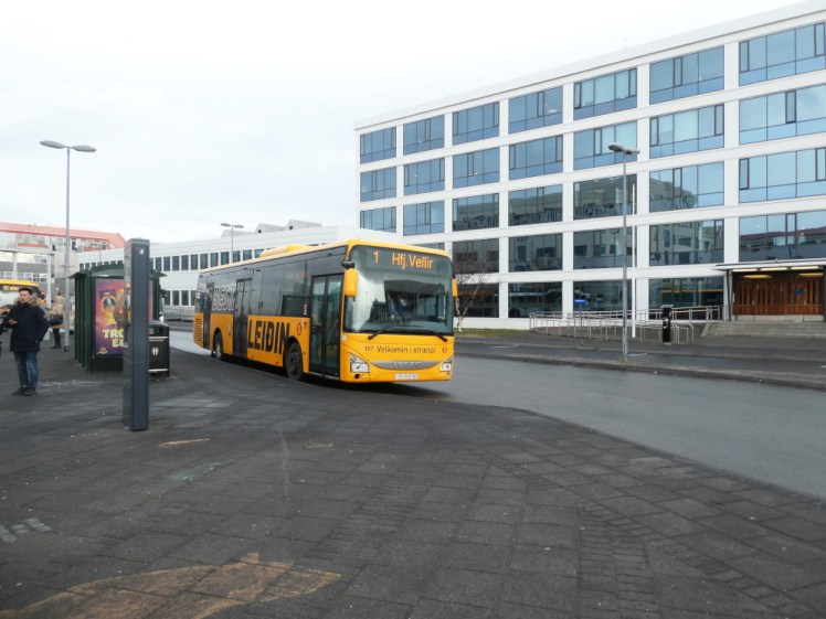 A yellow single-decker city bus parked at Hlemmur in downtown Reykjavik.