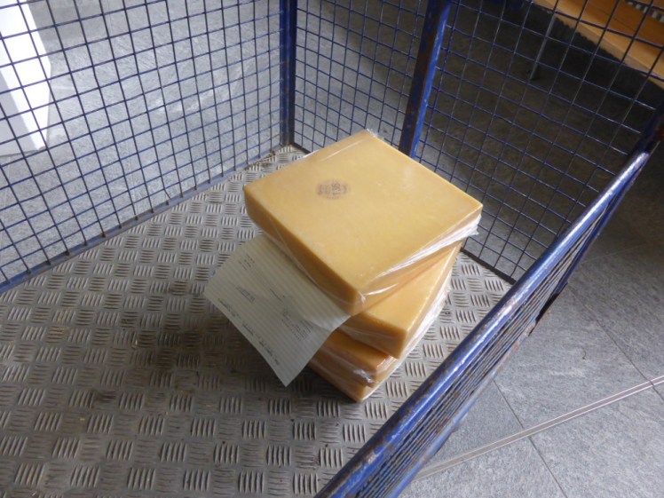 Four large square slabs of vacuum-packed cheese in a trolley.