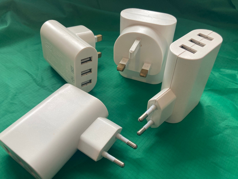 A pile of triple USD chargers, two with UK prongs and two with European prongs.