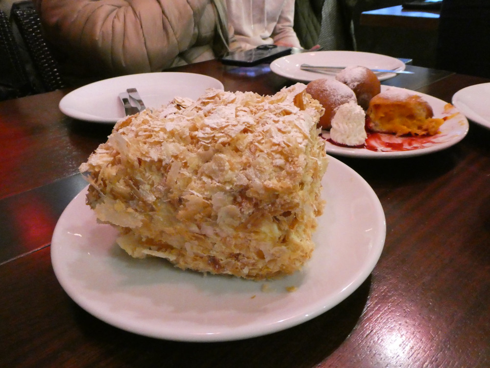 A giant flaky cake-thing with other plates and cutlery in the background for some size context.