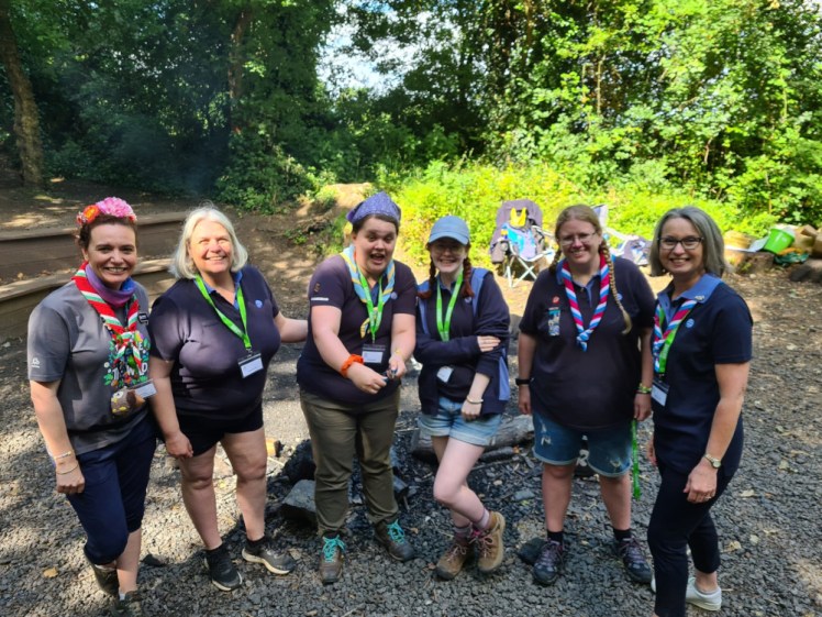 The campfire team at GLOW, all in navy polo shirts, with the Deputy Chief Guide at one end and the Region Chief Commissioner at the other.