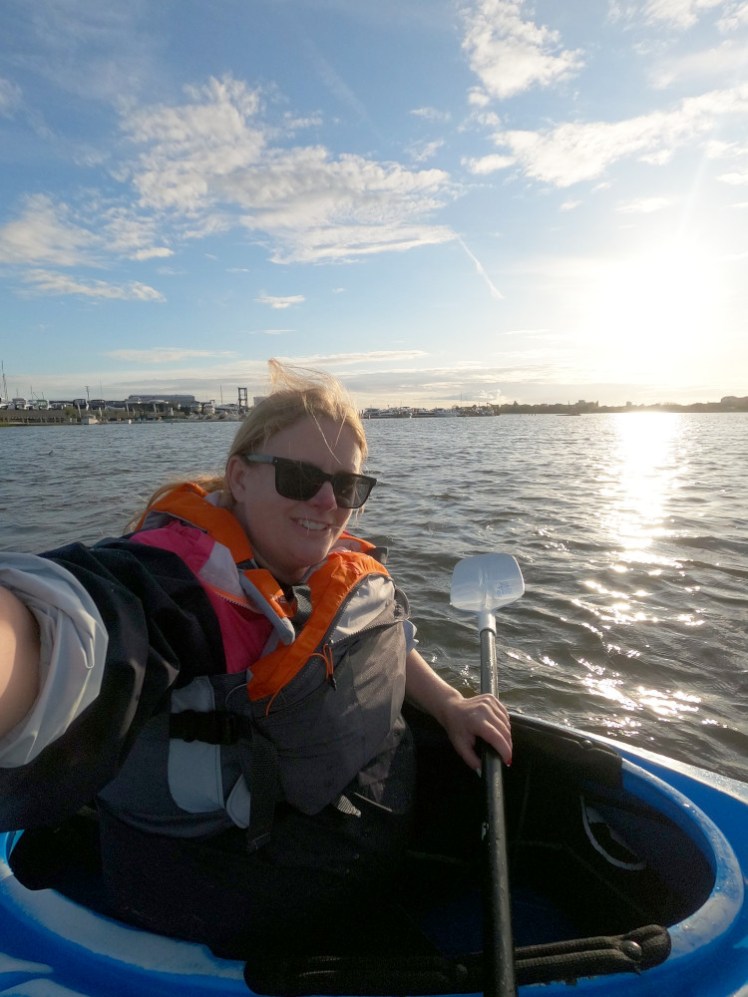 Me in a blue kayak taking a selfie straight into the sunset.