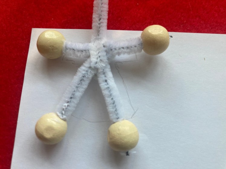 The skeleton with beads pushed on as hands and feet. It's lying on a piece of paper and I've sketched a robe around it.