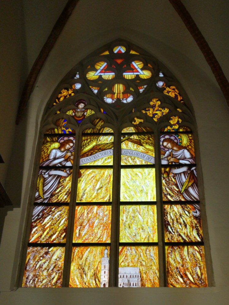 One of my favourite windows. At the bottom is a tiny church and the rest of the window is a riot of flame with angles in the top corner. I don't read Latin but I think it says something about construction being the glory of God.