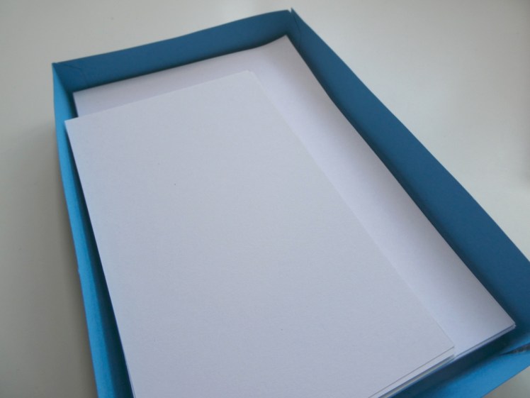 A blue cardboard tray containing two sizes of plain white unlined index cards.