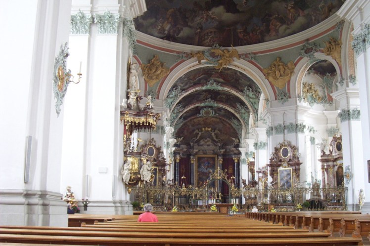 Inside St Gallen Cathedral, a Baroque church with its walls painted white but every space filled with elaborate green, gold and pink decoration.