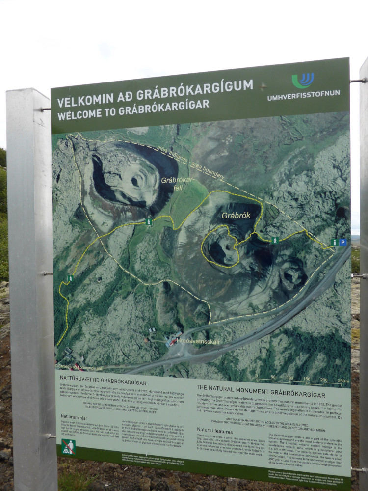 An information board showing the Grábrók cluster from above, with a route around them and some information in English and Icelandic at the bottom.