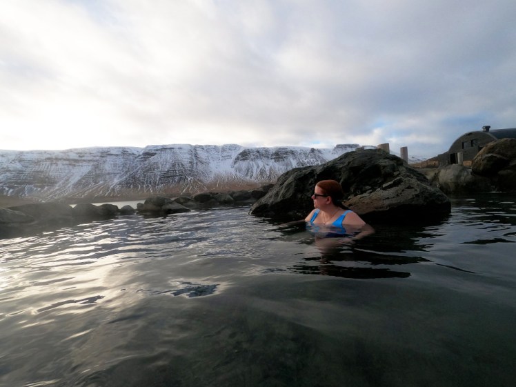 Me sitting in a rock pool with a row of snowy mountains behind me.