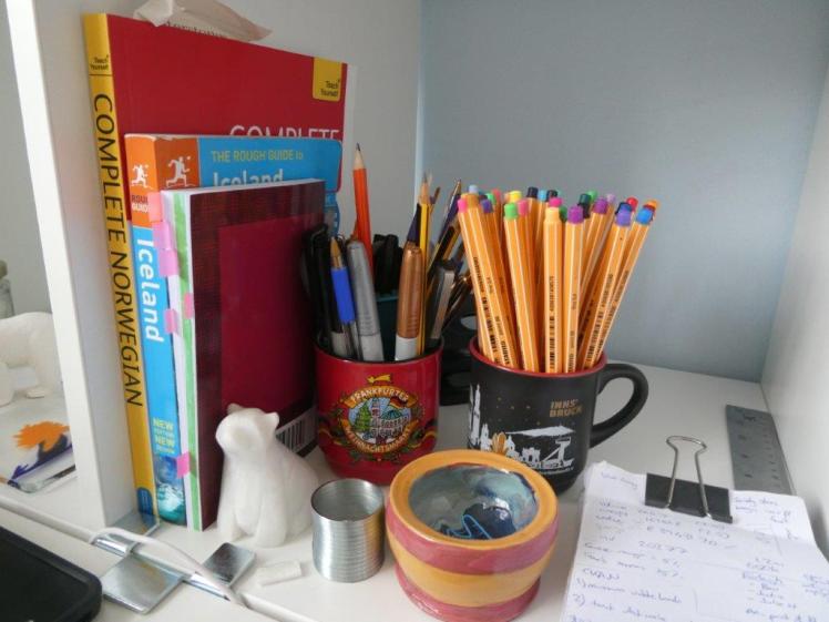 Close-up of the contents of my desk cube, featuring pen pot, reference books, notepad and stone polar bear.