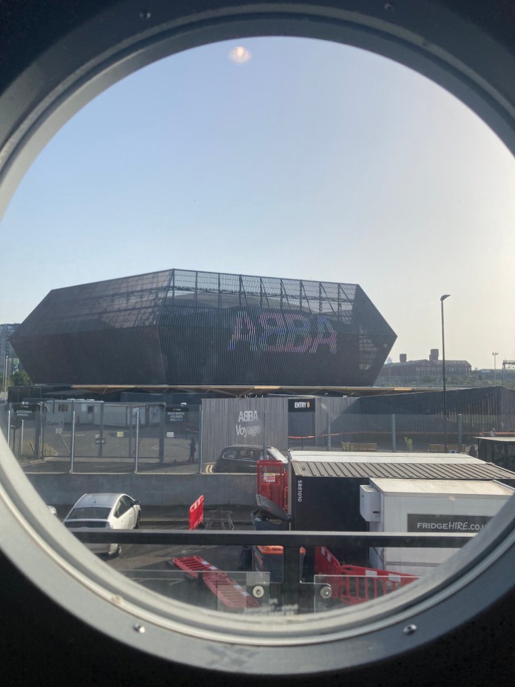 The view from my window, a round porthole in the hotel door. Directly opposite is a weird geometric structure with ABBA across it in huge letters.