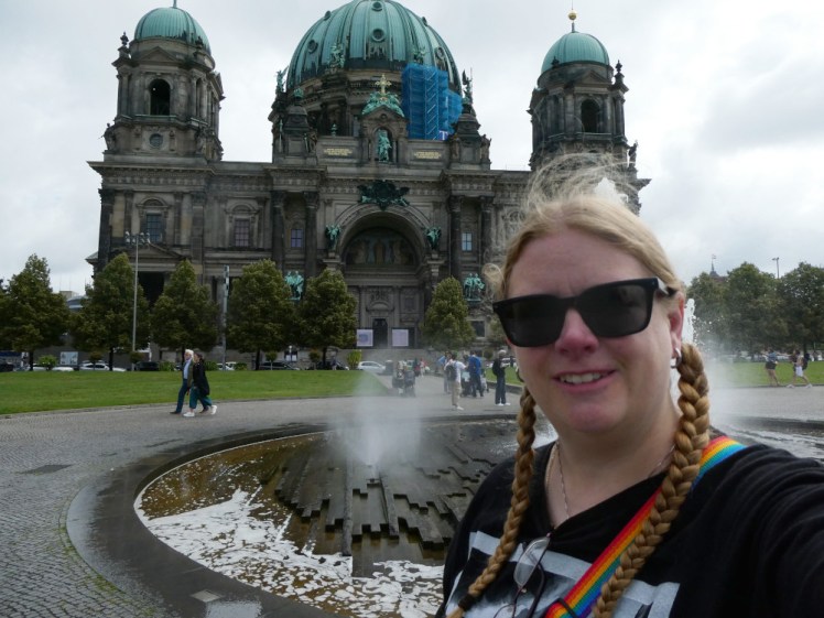 A selfie with Berlin Cathedral, a big stone thing with green copper domes. The stone looks like it badly wants cleaning - it's probably white but looks quite dark brown.