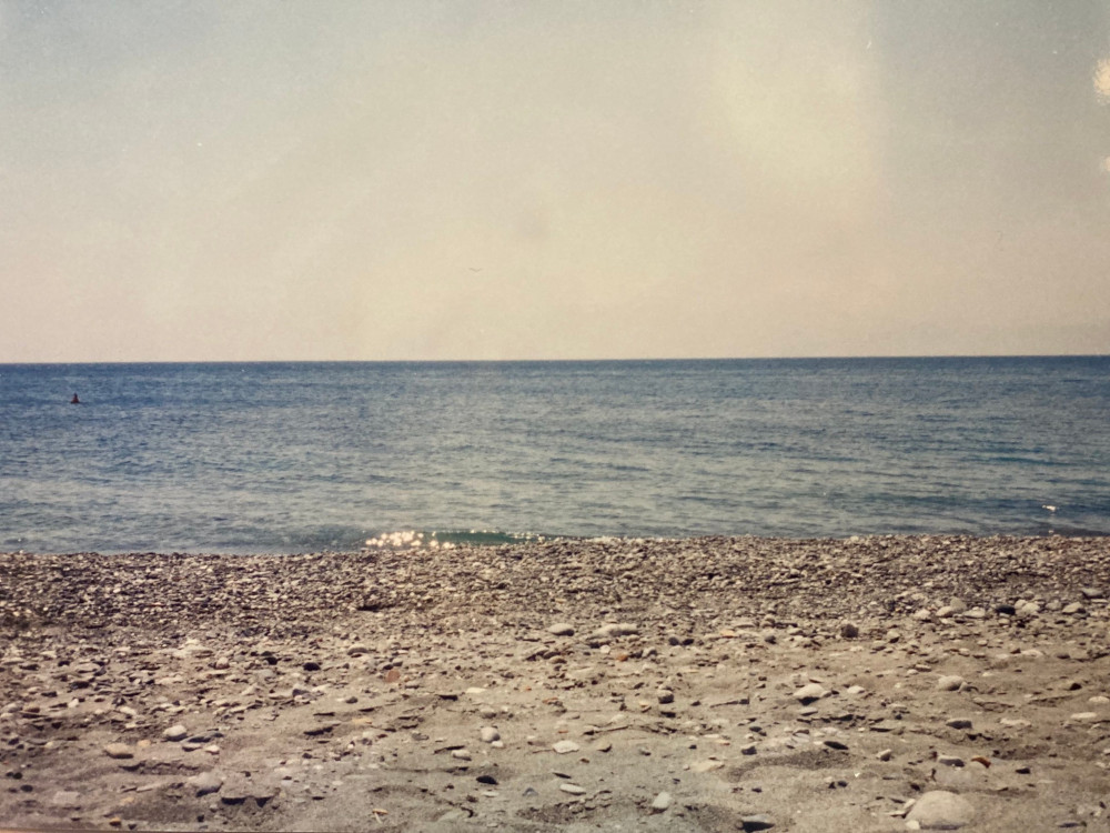 Our beach - a stony beach of grey-white sand and a bright blue sea, even though the haze the 35mm film.