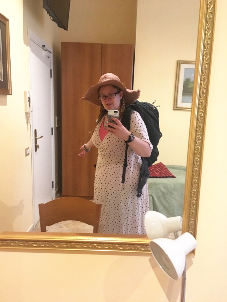 Hotel mirror selfie in Rome. I'm wearing a long pink dress with brown polka dots, a matching huge floppy pink straw hat and am carrying a dark grey 45l backpack.