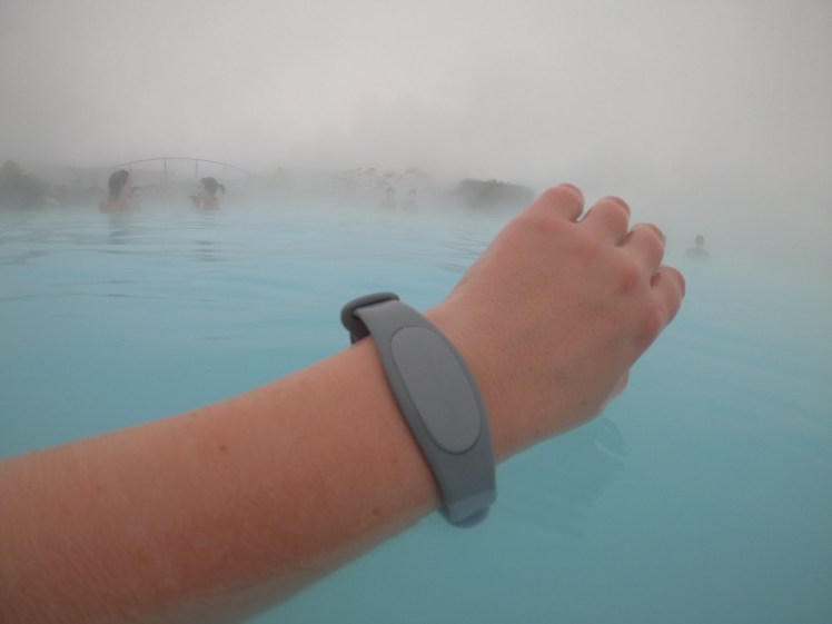 My arm sticking out of the Blue Lagoon on a misty day, wearing a wide grey silicon bracelet with an oval shape on top.