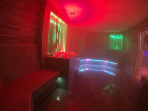 The very-strongly scented salt steam room. The walls are wooden, there's a red light in the ceiling, which rotates through to green). There are glass panels with bamboo decorations in the wall, lit in green. Underneath the benches are ropes of LED lights in purply-blue. The reality is a lot less garish than the photo, which is misty because there's a lot of steam in this room.