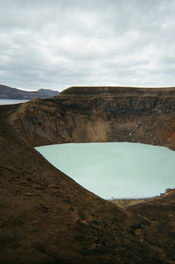 A pool of milky blue water in a muddy crater.