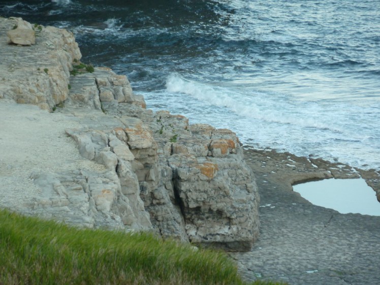 The pool at Dancing Ledge, a shallow rectangular pool in the rock platform. Behind it, the sea rolls, demonstrating why you don't swim there.