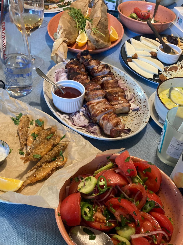 More food - you can see fish cooked in brown paper parcels, sliced pork, small whole-fried fish, another dish of tomato & cucumber and a hint of a rice dish just disappearing off the bottom.