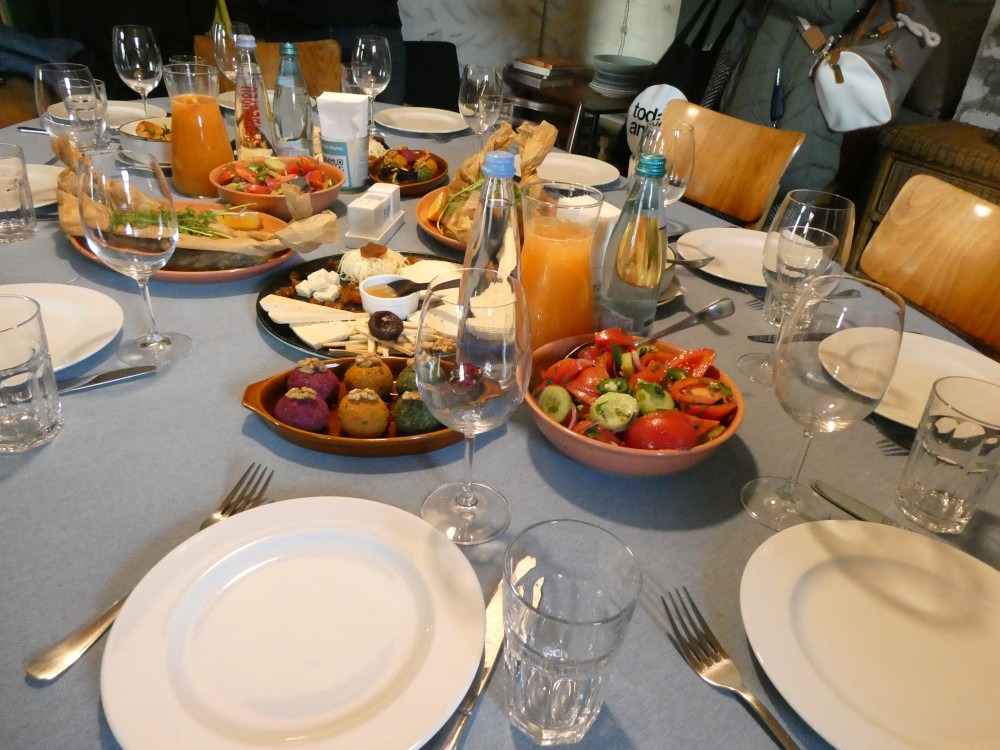 An oval table laid out with dishes of colourful food and jugs of fruit juice.