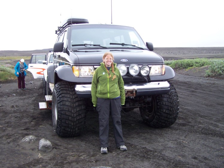 Me in July 2013, wearing a green fleece, leaning against the front of a big black jeep. The car's Ford badge is about level with my nose and its rack of headlights with my shoulders.