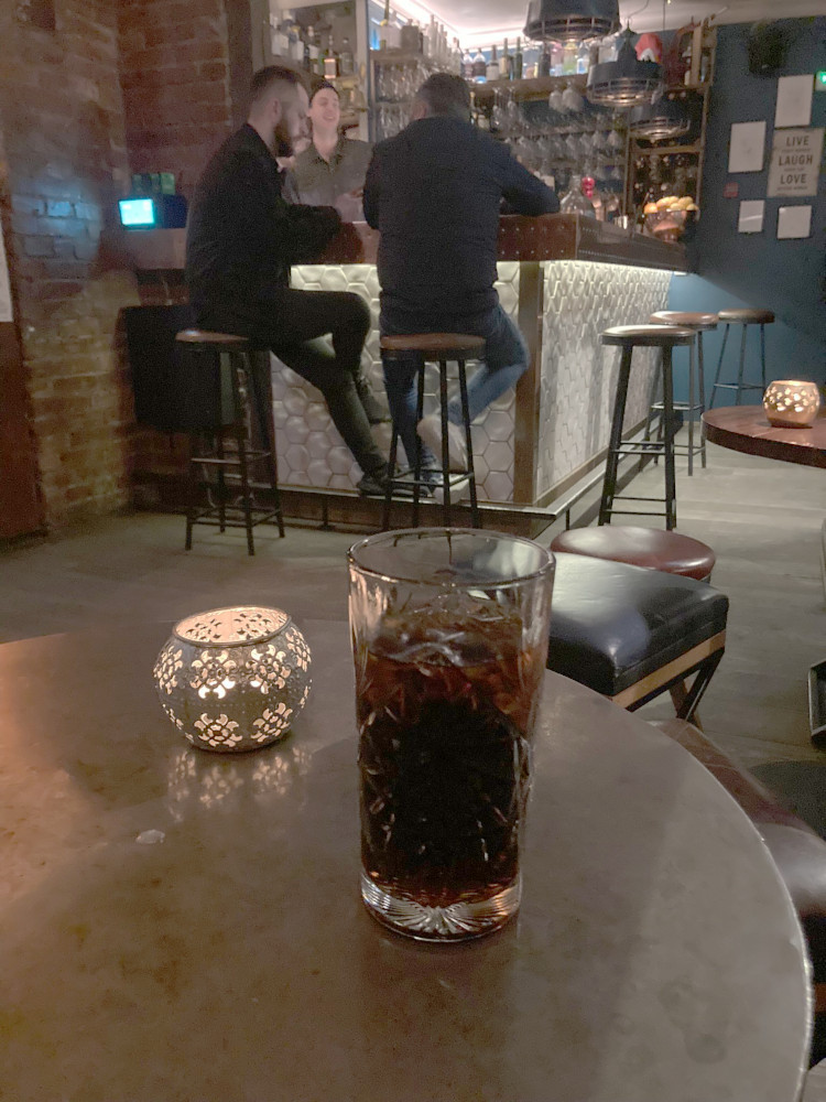 A glass of full-fat Coke in a patterned glass on a table in a bar in Reykjavik.