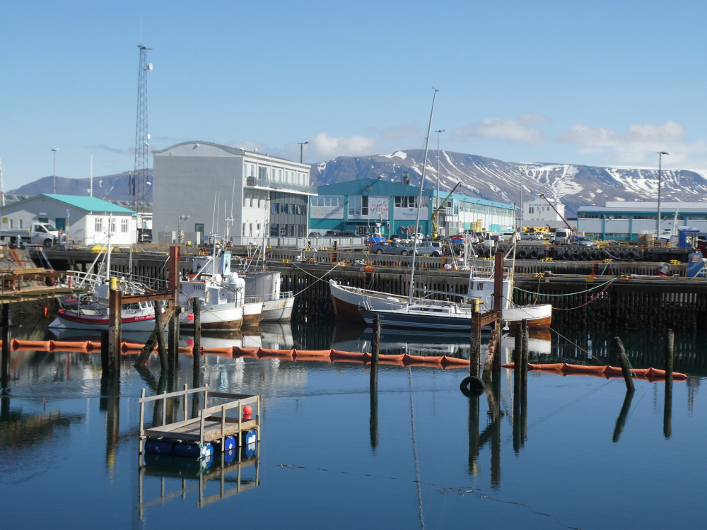 Reykjavik Old Harbour, deep blue water surrounded by colourful industrial buildings, fishing equipment and boats.