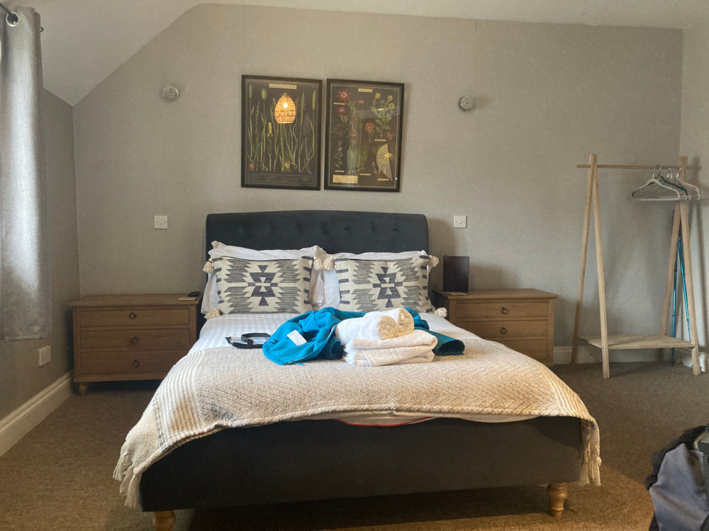 My big double bed in a light airy room over a pub. There are illustrations of local flora over the bed and I've chucked my blue softshell on among the blanket and the towels.