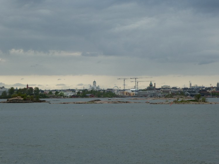 Helsinki's skyline plus cranes as seen late on a cloudy summer evening.