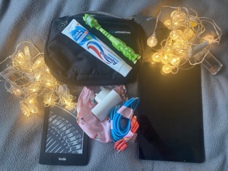 The non-wearable things I used: two sets of battery-powered fairy lights, a washbag, charging kit, tablet & Kindle, all lying on a grey fleece blanket.