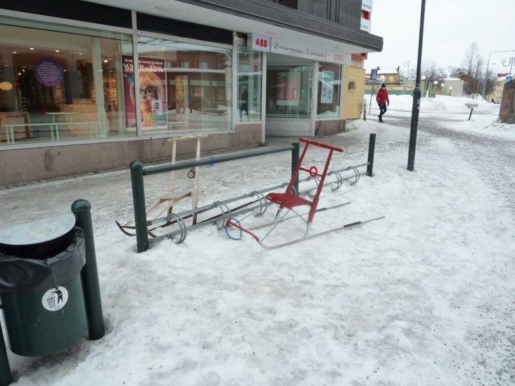 Two lightweight wire and wood shopping sledges locked up outside a shop.