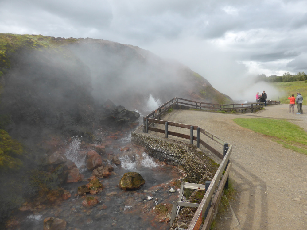 Deildartunguhver in 2014. A stream of boiling water sends up fountains and a ludicrous amount of steam. Tourists are kept out of the water by a wooden fence. By 2022, it's been replaced by a higher stainless steel fence but it was producing too much steam to get as good a photo as this last week.