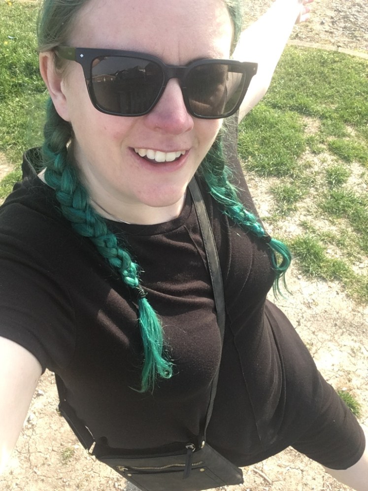 Selfie early on in lockdown with green hair. It's the sort of teal where it's supposed to be blue and as usual, I'm wearing it in two plaits. I'm also wearing a long black t-shirt and black leggings rolled up to my knee because