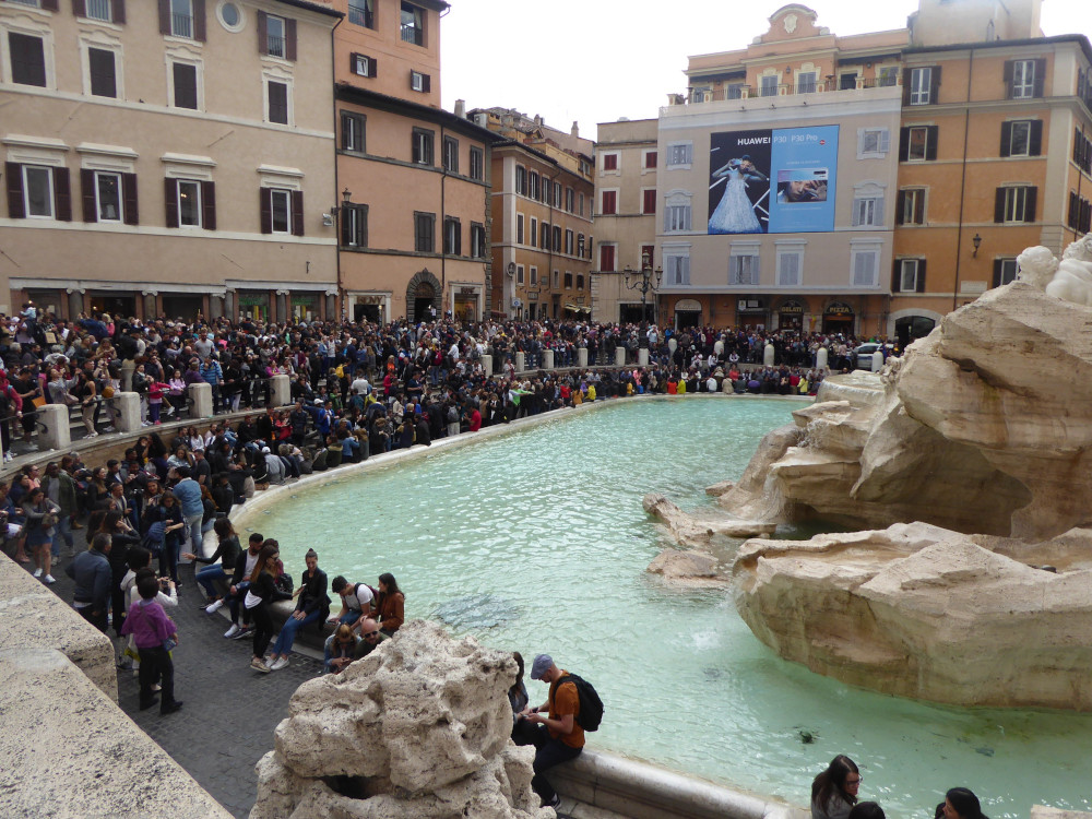 Thousands of people crammed into a square between the shops and the dish of the Trevi Fountain.