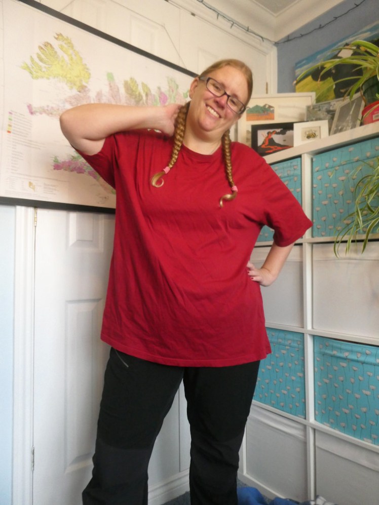 Posing with a hand behind my neck in a big plain darkish red t-shirt.