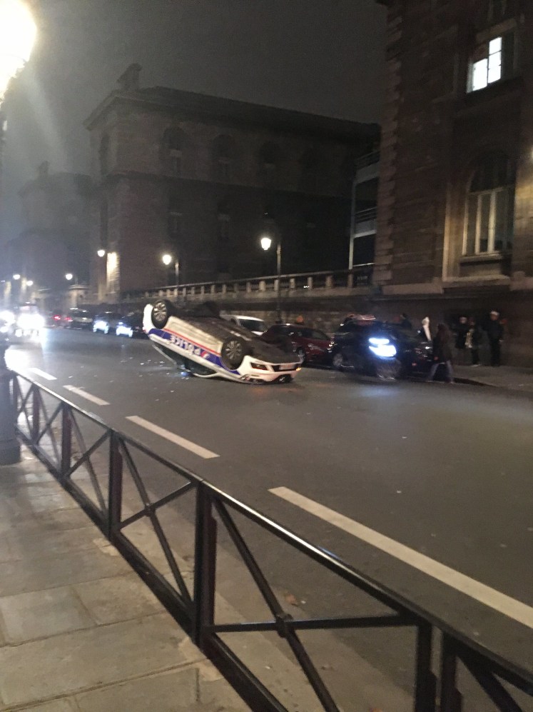 Police car on its roof after gilets-jaunes riots