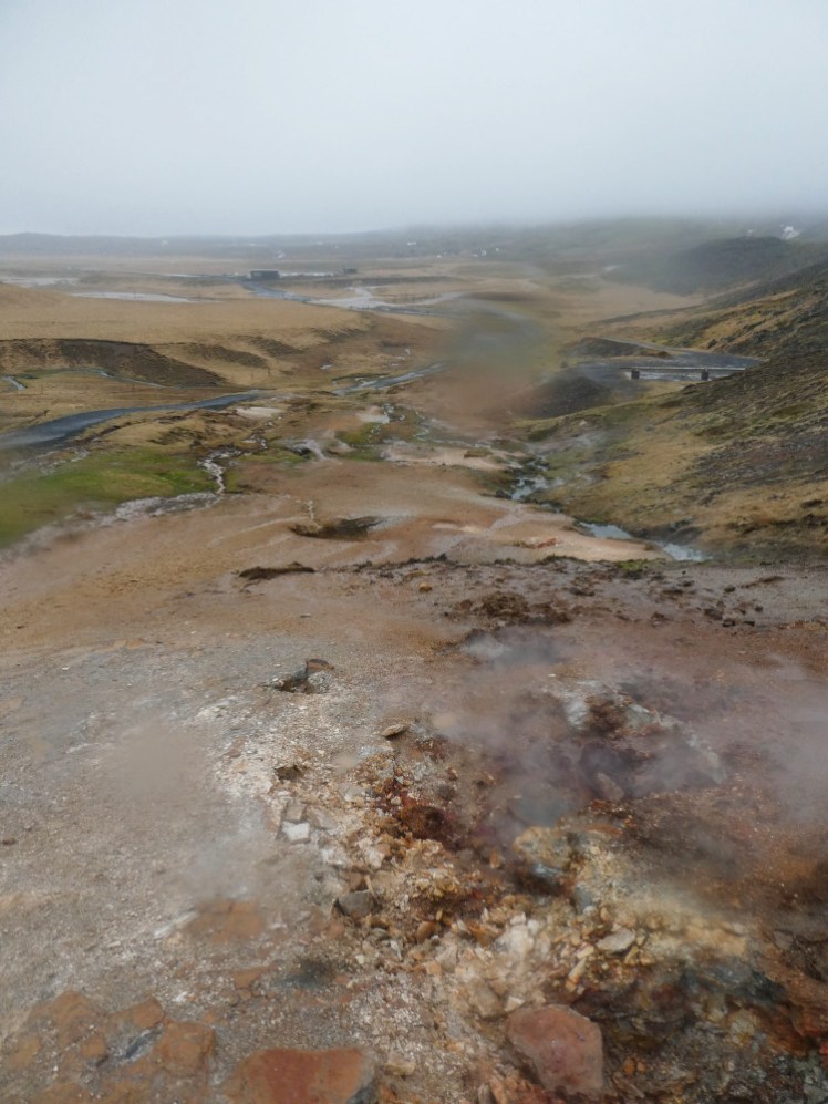 Ten minutes in, looking down the mountain to the village, which is lost in cloud. In the foreground is the white and blistered bit of earth where steam and sulphur rises, bubbles and steams. Everything else is kind of orange and wet and there's a raindrop on the lens that I haven't noticed.