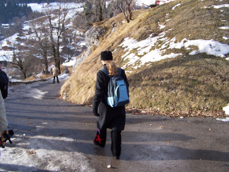 Me walking away from the camera down a wet slushy hill. I look quite militaristic in my long wool coat, black fleece hat and gloves but now you can see I'm wearing my favourite black bootcut cords with huge colourful stars appliqued onto the lower legs.