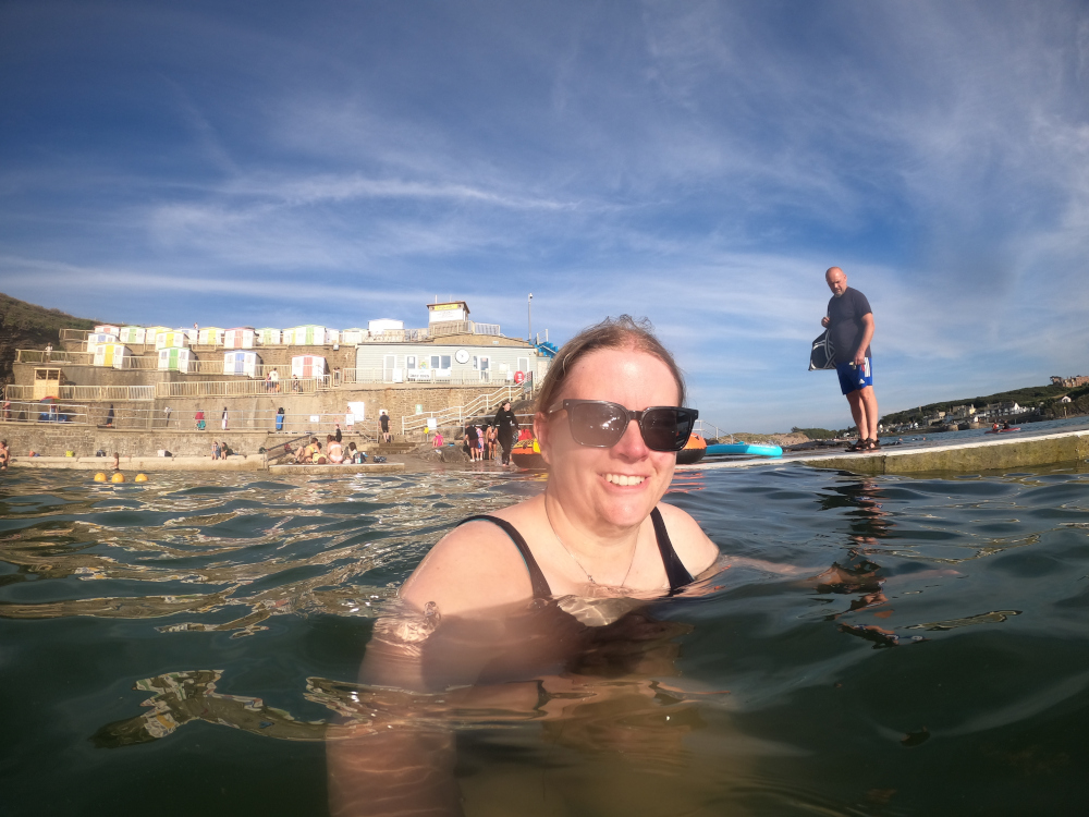A selfie in Bude Sea Pool with the terraces and beach huts glowing in the evening sun behind me.