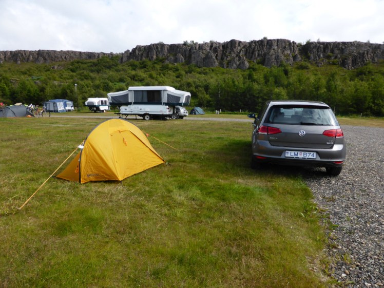 My tent and grey VW on the main field in 2015, with a basalt cliff along the back of the campsite.