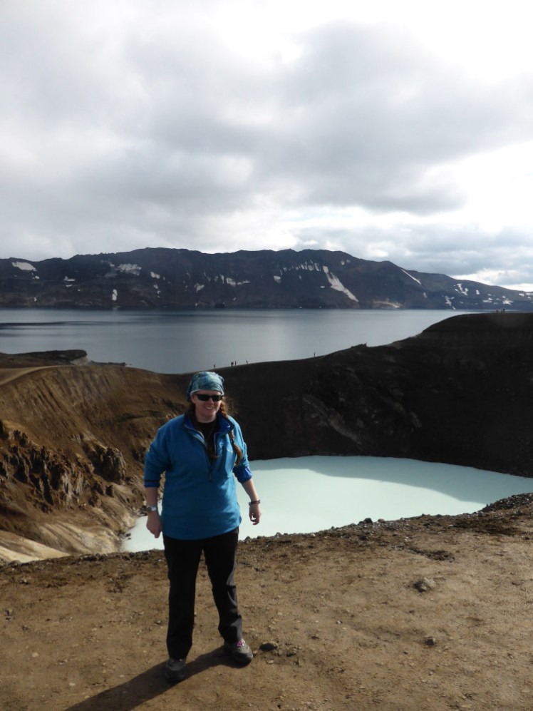 Me at Askja in 2016. Behind me is a milky flooded crater and behind that a vast and terrifying navy blue crater lake.
