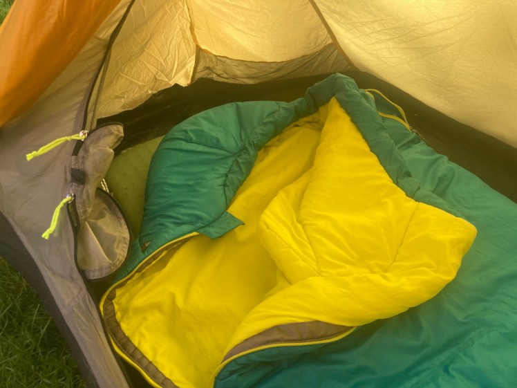 My green sleeping bag folded over in the tiny tent so you can see the bright yellow lining.