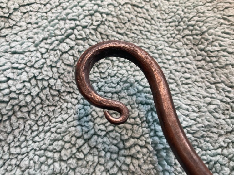 A beautifully curled crook in my steel poker, slightly reddened now, on a background of sage green fleece.