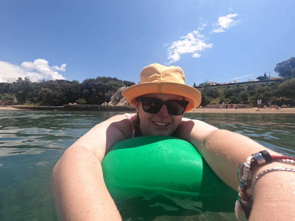 A two-handed selfie in the water, literally leaning across a green drybag floating on the water.
