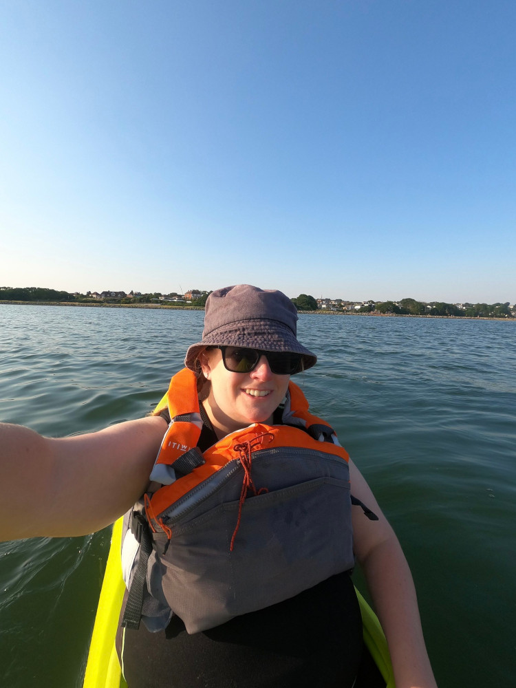Boat club in the summer. Me in a t-shirt and sleeveless wetsuit & buoyancy aid, sitting in a green-yellow kayak with bright sunshine just out of shot.