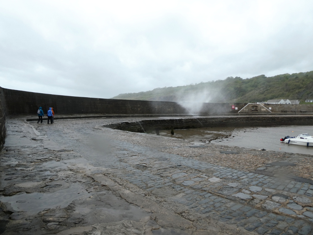 Lyme Regis Cobb with a wave breaking violently over the stone wall.