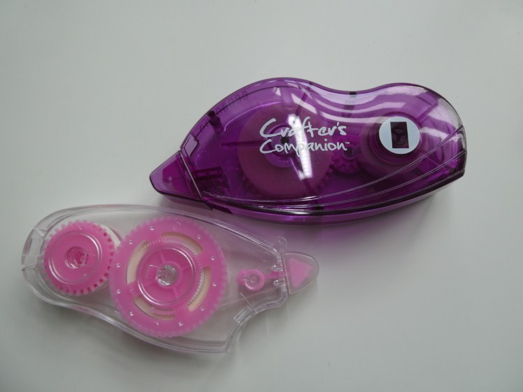 Two tape runners or glue mice. Plastic mouse-shaped things with a roll of double-sided tape inside