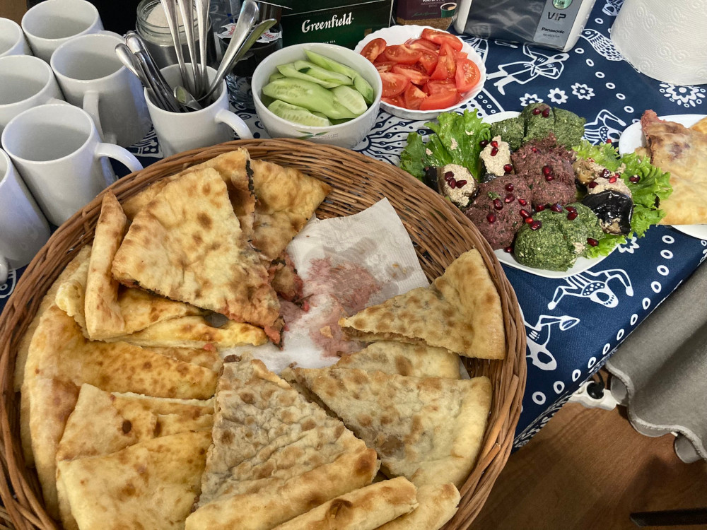 Lunch at Ikorta - a basket of khachapuri, a place of pkhali and dishes of tomato and cucumber.