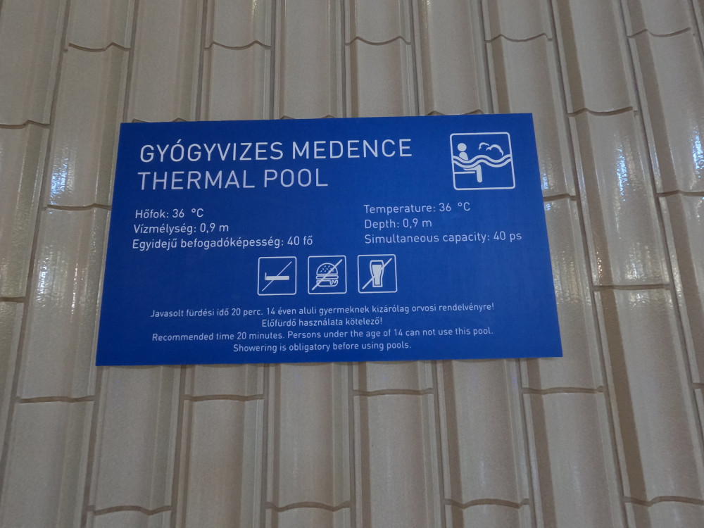A sign on the wall with information about the pool, including its depth, temperature and capacity.